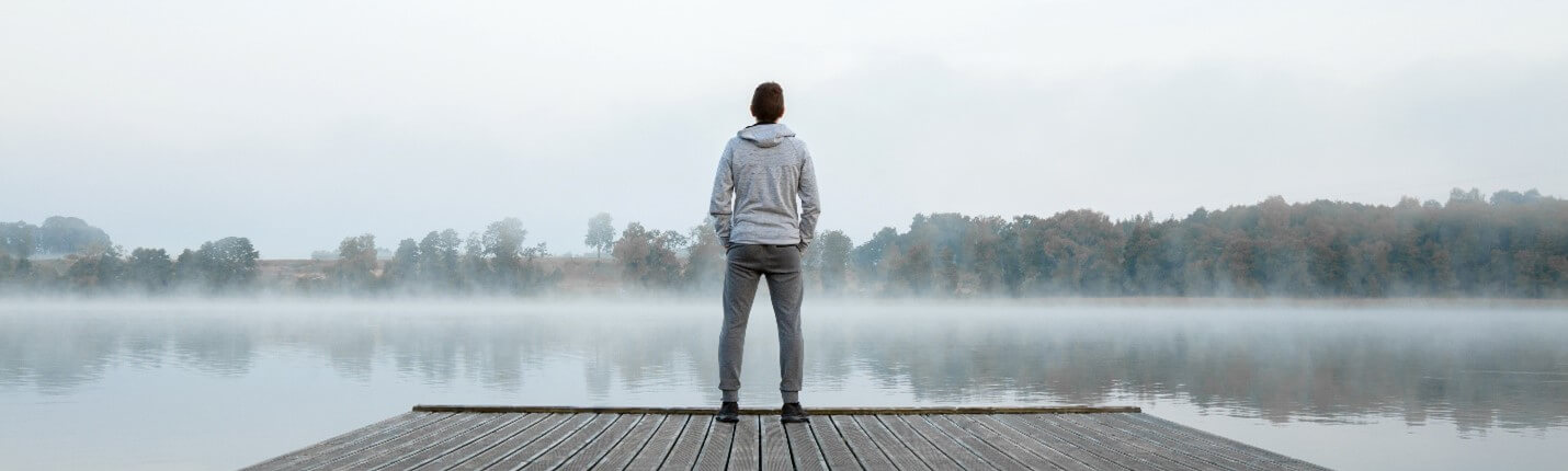 Man standing on dock looking out at lake